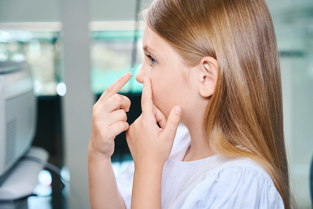 Pediatric patient placing her pediatric contact lenses in her eye. 
